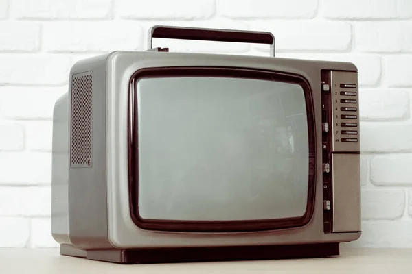 Stary telewizor na tle ściany Cegła biała. — Zdjęcie stockowe