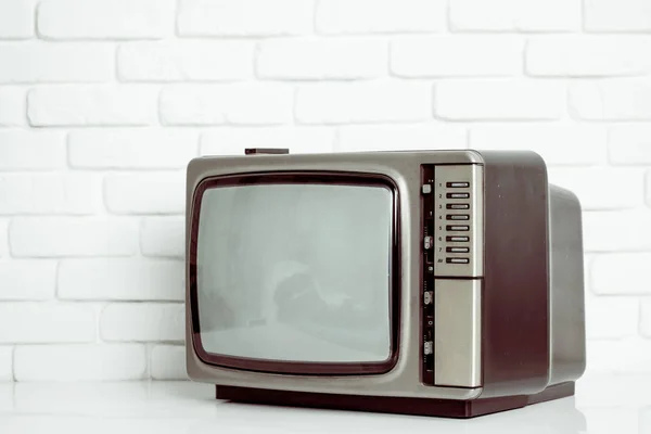 Stará televize na pozadí bílá cihlová zeď. — Stock fotografie