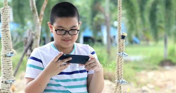 Feliz Asiático Criança Mão Segurando Celular Balanço Cadeira Com Sorriso — Vídeo de Stock