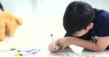 Asyalı çocuk dinlenme katta ve renkli kalem ile boyama.