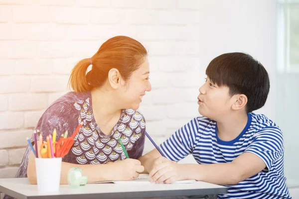Азиатский мальчик с матерью, который учит и изучает домашнюю работу дома — стоковое фото