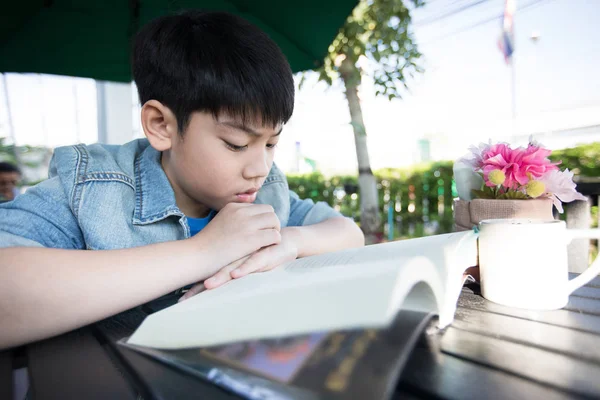 Asian Cute little boy reading book with serious face . — Stock Photo, Image