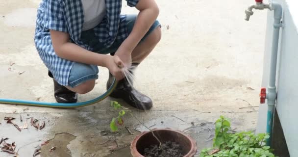 小亚细亚的泰国男孩在花园里的黑土上浇水 地球日概念 — 图库视频影像