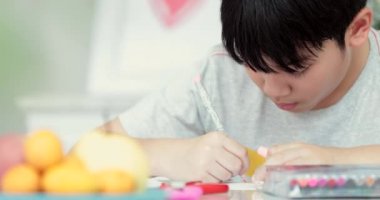 Kalem tutan ve ödevini evde yazma mutlu Asya sevimli çocuk el.