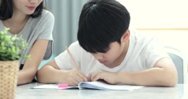 Asya anne oğlu evde okulun ödevlerini yapmak için yardımcı oluyor.