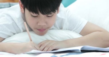 Kalem tutan ve ödevini evde yazma mutlu Asya sevimli çocuk el.