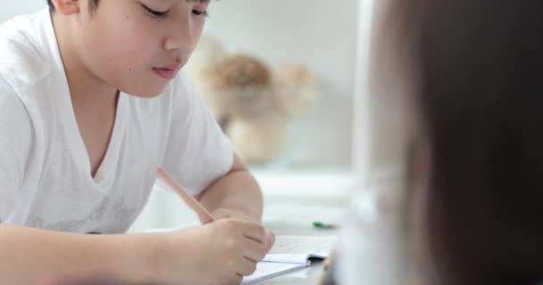 アジアのかわいい少年の幸せ手鉛筆を押し 家で宿題を書く — ストック動画