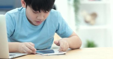 Şirin Asyalı çocuk izleyin ve sessizce yüzü ile tablet bilgisayarda oynama.