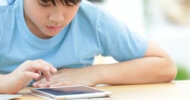 Şirin Asyalı çocuk izleyin ve sessizce yüzü ile tablet bilgisayarda oynama.