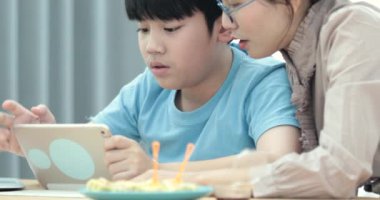 Genç Asyalı anne izliyor ve tablet bilgisayar birlikte evde oynarken oğlu ile.