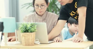 Mutlu aile evde online alışveriş bir dizüstü bilgisayar kullanarak. Ve tablet bilgisayar arka plan üzerinde oynayan genç Asyalı çocuk .