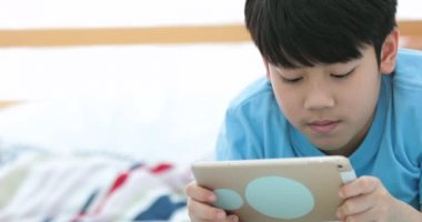 Şirin Asyalı çocuk izleyin ve sessizce yüzü ile tablet bilgisayarda oynama.