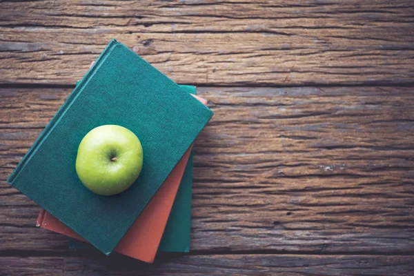Zelené jablko na knihy s dřevěnými pozadím. — Stock fotografie