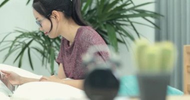 Asyalı kadın yatakta web taramak için onu laptop kullanıyor