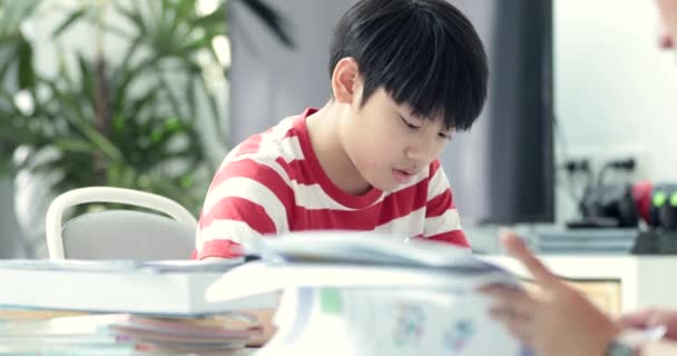 リビングで宿題の息子と深刻なアジアの母 お母さんが息子を教えている天才の作り方 — ストック動画