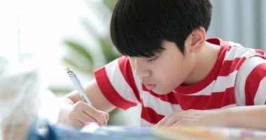 Evde ödevini yapıyor ciddi Asyalı çocuk.