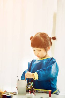 Okuyamayacağı boyalar ile oynarken küçük şirin bir kız portresi.