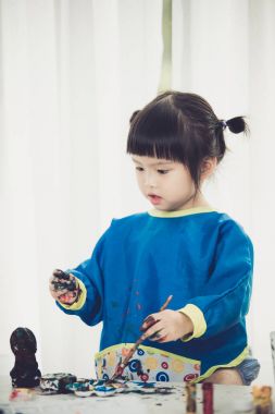 Okuyamayacağı boyalar ile oynarken küçük şirin bir kız portresi.