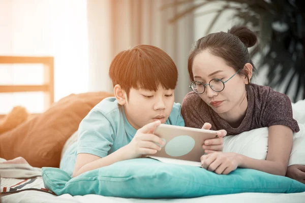 Ázsiai fiú anyjával, játék és tanulás tabletta számítógép — Stock Fotó