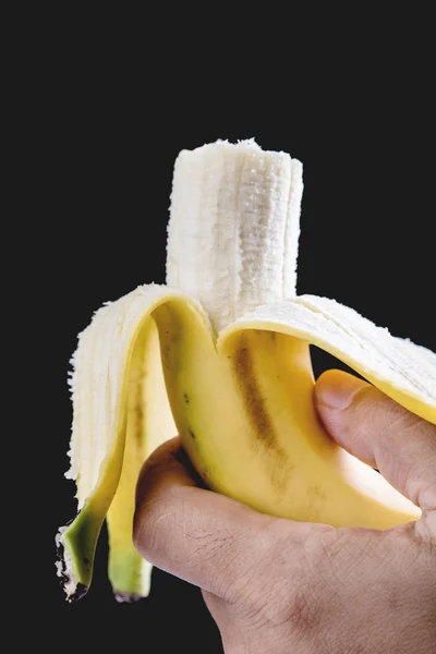 Banane in der Hand auf schwarzem Hintergrund — Stockfoto