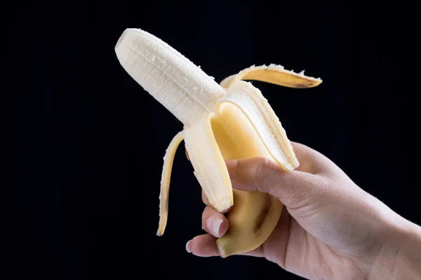 Banane in der Hand auf schwarzem Hintergrund — Stockfoto