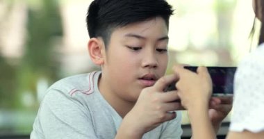 Mutlu aile anne ve oğlu mobil cep telefonuyla birlikte oyun oynarken.
