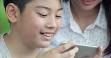 Mutlu aile anne ve oğlu mobil cep telefonuyla birlikte oyun oynarken.