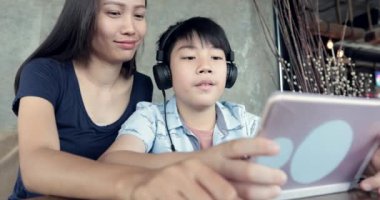 Asyalı kadın çocukla café'de tablet bilgisayar kullanarak.