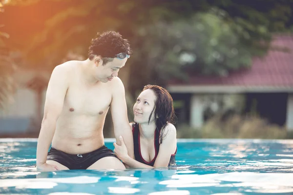 Young asian couple relaxing in swimming pool