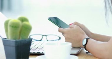 Bir smartphone kullanarak ve dizüstü bilgisayarda yazarak kadın.