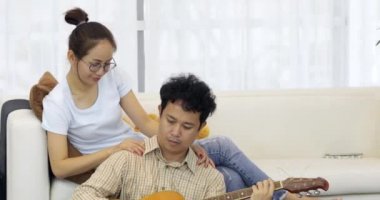 Asya adam serenat tatlım gitar kadınla erkek sanatsal amaçlı sığ derinlikte evde görünüyor.