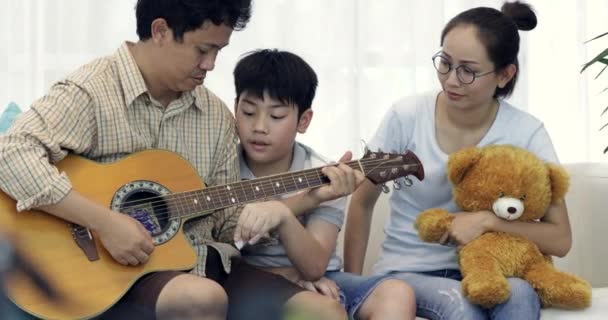 Glad Asiatiska Far Spela Gitarr För Hans Familj Hemma — Stockvideo