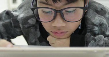 Gözlük takan ve tablet bilgisayar, dijital tablet üzerinde oyun genç genci kullanarak Asya yakışıklı .