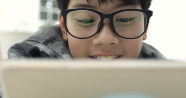 Gözlük takan ve tablet bilgisayar, dijital tablet üzerinde oyun genç genci kullanarak Asya yakışıklı .