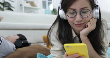 Rahatlatıcı ve genç çocuk oturma odasında tablet bilgisayarda oynama ile müzik Genç Asyalı kadın.