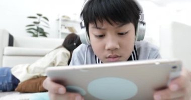 Rahatlatıcı ve genç çocuk oturma odasında tablet bilgisayarda oynama ile müzik Genç Asyalı kadın.