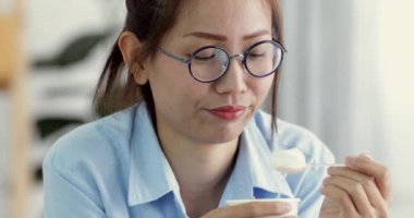 Mutlu Asyalı kız zevk gülümsemek yüz evde dondurma yeme.