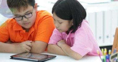 4k, okul çocukları bir kadın öğretmenle sınıfta tablet bilgisayarlar ile çalışma.