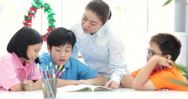 年轻的亚洲老师在课堂上帮助年幼的学生 — 图库视频影像