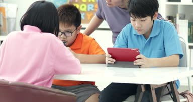 Asyalı öğretmen ve üç çocuklar kendilerini eğlenceli dijital sekmesine gidin ve gülüyor