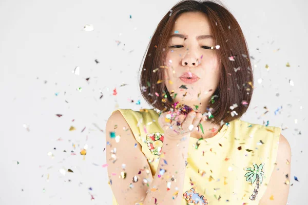 Femme asiatique s'amuser avec des confettis colorés sur fond gris — Photo