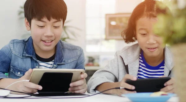 Garçon et fille jouer avec téléphone intelligent et tablette à la maison — Photo