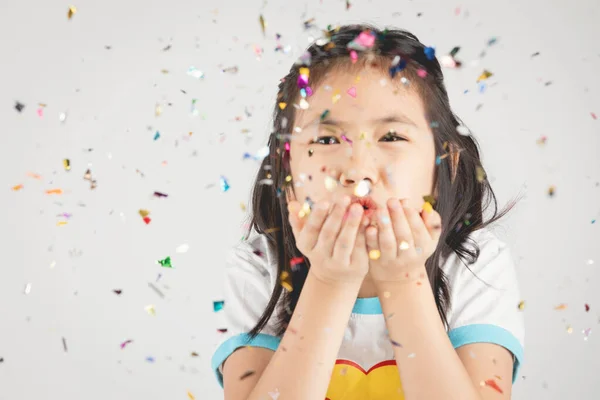 Asian girl having fun with colorful confetti on gray background. Stock Picture