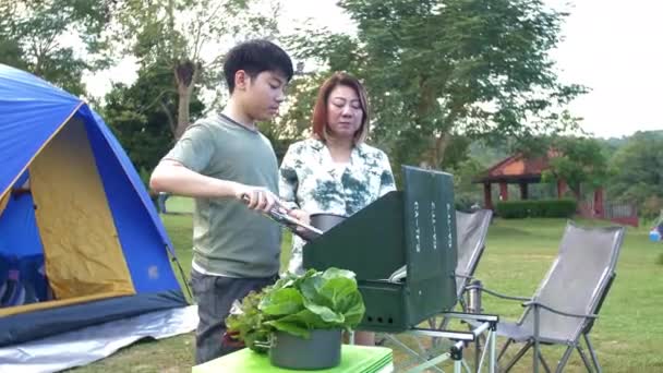 아시아 엄마와아 저녁으로 바베큐를 만들고 있습니다 즐겁게 캠핑을 — 비디오