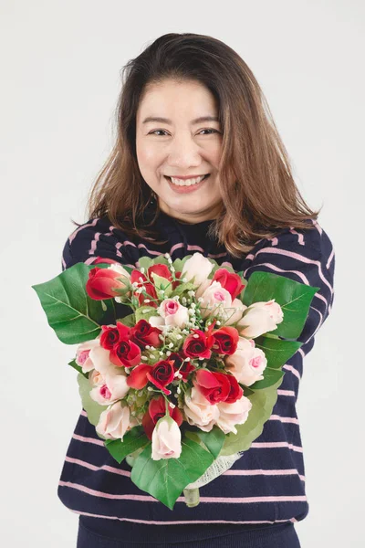 Asiatico sorridente donna su grigio studio colpo con rosso rosa fiore . — Foto Stock