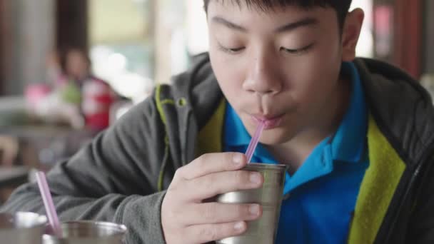 亚洲少年坐在家里用塑料管喝水 — 图库视频影像