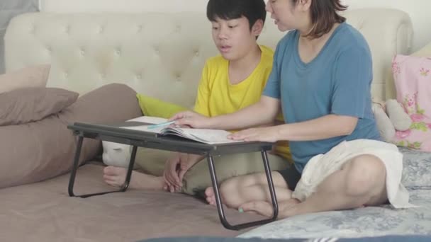 息子と母は寝室で宿題をしている 母は息子に基礎的な分析を理解する方法を教える — ストック動画