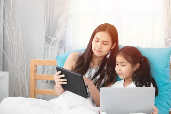 Dos lindo asiático niño niñas usando tableta y portátil en cama . —  Fotos de Stock