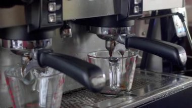 Kahve makinesi kahve bardağında buharla kaplı iki fincanda espresso yapıyor.
