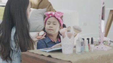 Genç Asyalı kadın blogcu makyaj ve kozmetik ürünlerini gösteriyor. Kızlar video kaydını evdeki oturma odasında canlı yayınlamak için kamera kullanıyorlar. İş çevrimiçi etkileyici kavramı.